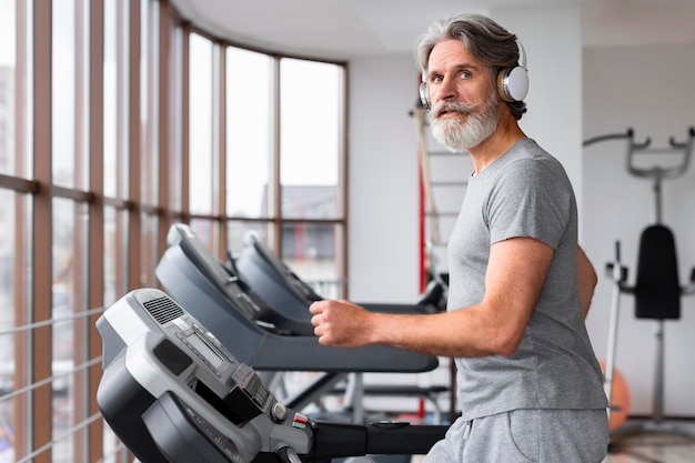 Uomo di vista laterale in palestra sul tapis roulant