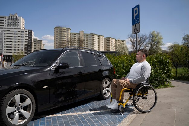 Uomo di vista laterale in sedia a rotelle vicino all'auto