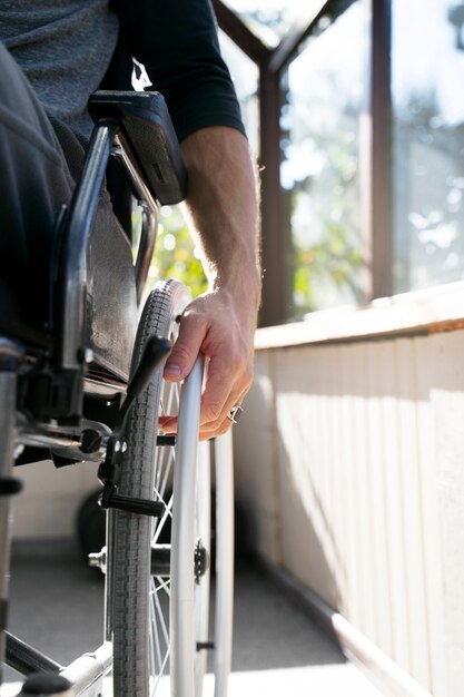 Uomo disabile ad angolo basso in sedia a rotelle