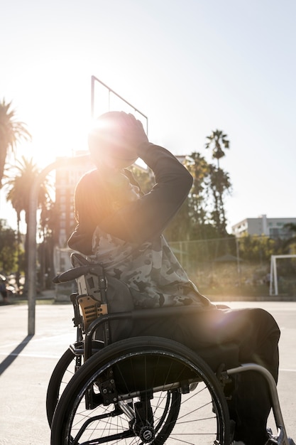 Uomo disabile in sedia a rotelle che gioca a basket