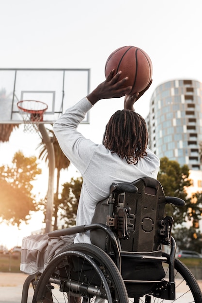 Uomo disabile in sedia a rotelle che gioca a basket