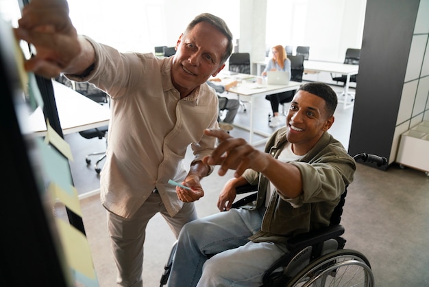 Uomo disabile su una sedia a rotelle che lavora nel suo lavoro d'ufficio