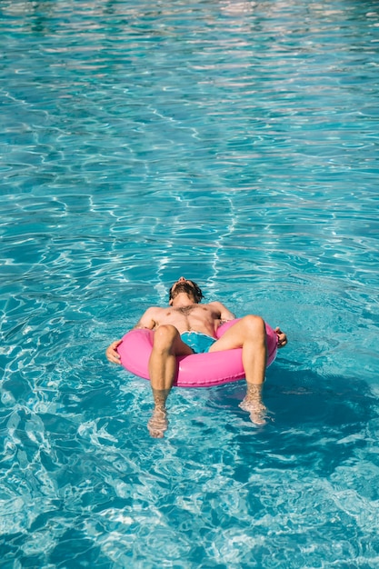 Uomo dormire su anello gonfiabile in piscina