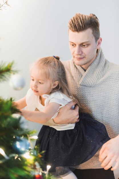 Uomo e bambino accanto all&#39;albero di Natale illuminato