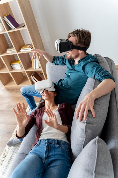 Uomo e donna a casa sul divano utilizzando l'auricolare per realtà virtuale