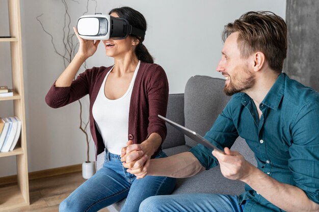 Uomo e donna a casa utilizzando cuffie da realtà virtuale e tablet