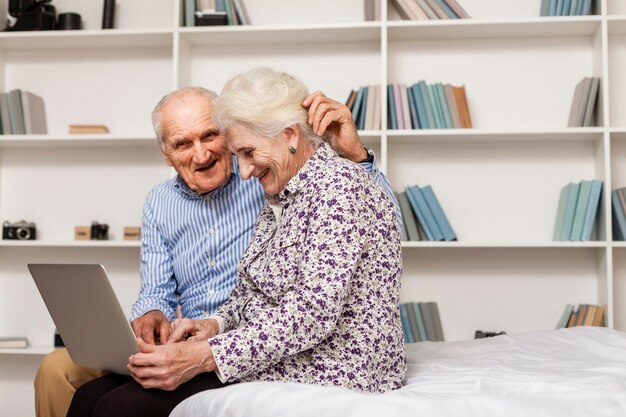 Uomo e donna adorabili che per mezzo di un computer portatile