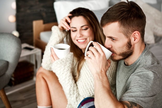 Uomo e donna allegri che bevono caffè in camera da letto