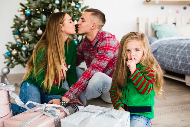 Uomo e donna che bacia davanti all&#39;albero di Natale