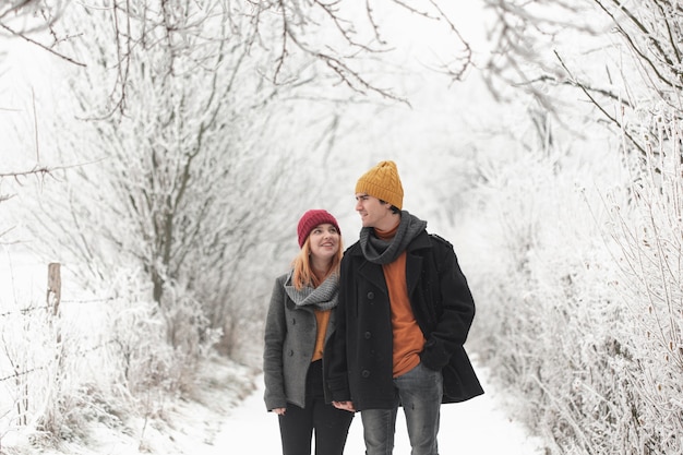 Uomo e donna che camminano nella foresta di inverno