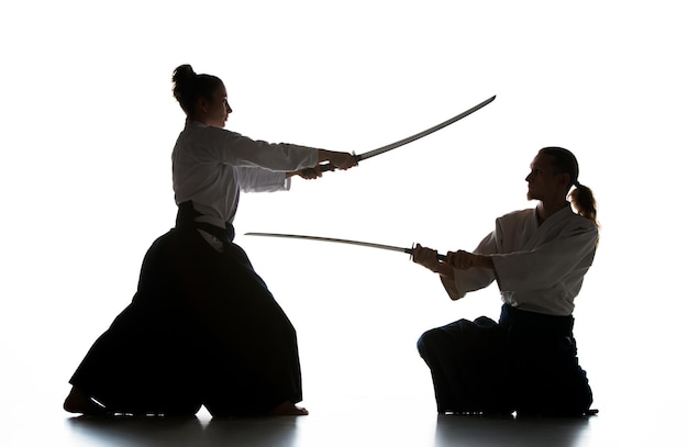 Uomo e donna che combattono e si allenano aikido sulla parete bianca dello studio