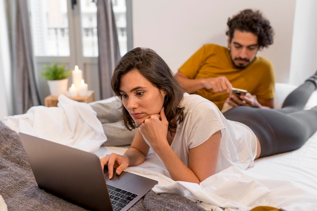 Uomo e donna che controllano i loro dispositivi a casa