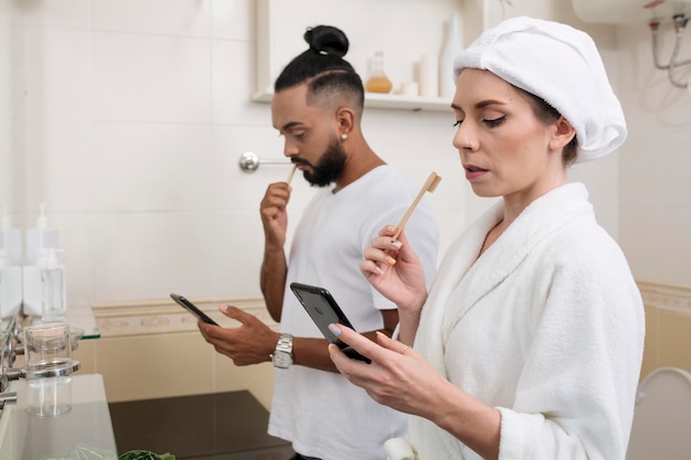 Uomo e donna che controllano i loro telefoni anche nel loro bagno