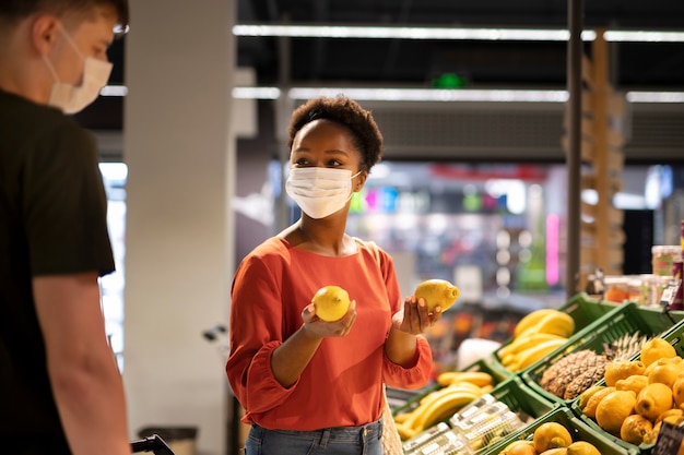 Uomo e donna che fanno la spesa al supermercato mentre indossano maschere mediche