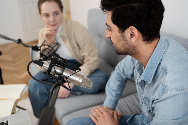 Uomo e donna che gestiscono insieme un podcast in studio