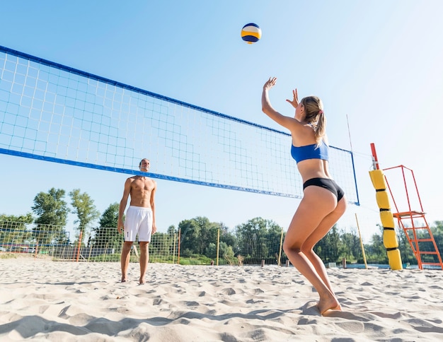 Uomo e donna che giocano a beach volley