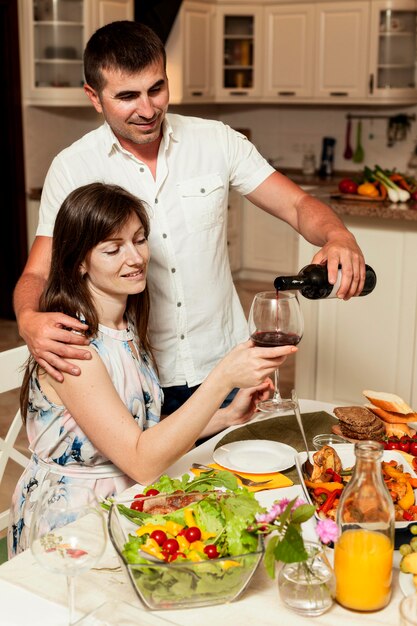 Uomo e donna che godono del vino al tavolo da pranzo