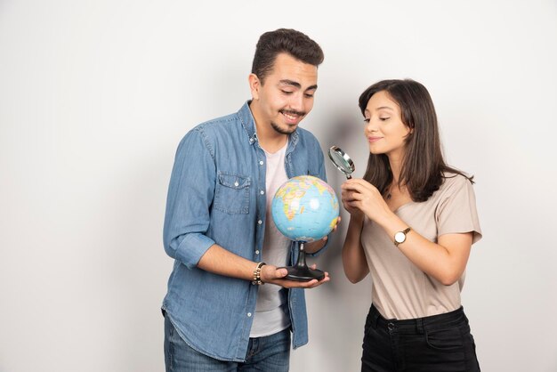 Uomo e donna che guardano sul globo su bianco.