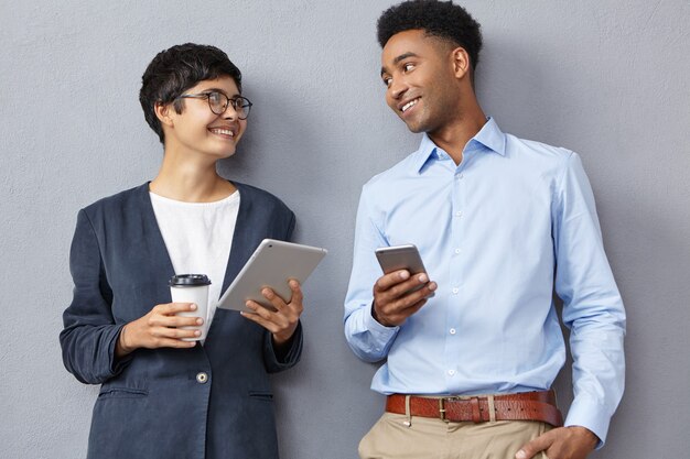 Uomo e donna che indossano abiti formali e che tengono telefono e tablet