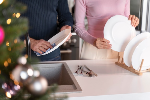 Uomo e donna che lavano i piatti insieme a natale