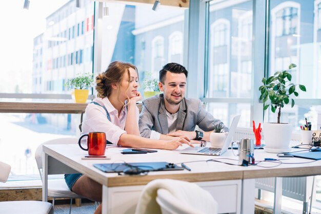 Uomo e donna che lavorano insieme al computer portatile