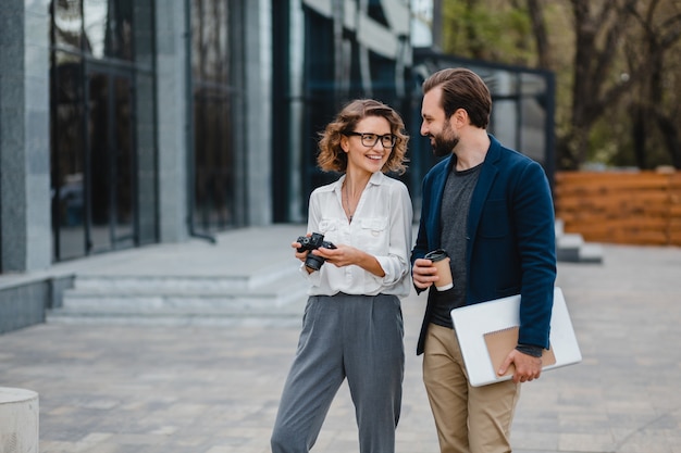 Uomo e donna che parlano nel centro urbano, discutono, scattano foto per progetti su una fotocamera digitale