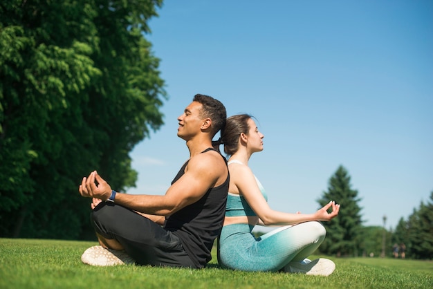 Uomo e donna che praticano yoga all&#39;aperto