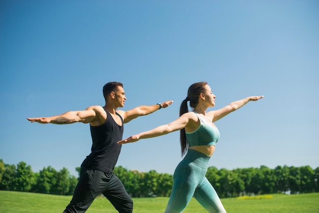 Uomo e donna che praticano yoga all&#39;aperto