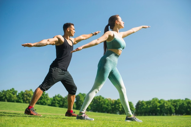 Uomo e donna che praticano yoga all&#39;aperto