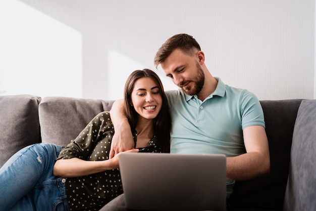Uomo e donna che si siedono sul sofà con un computer portatile