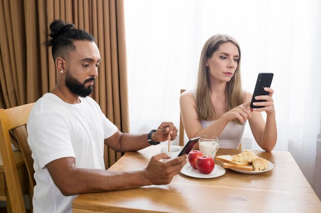 Uomo e donna che usano il telefono in cucina