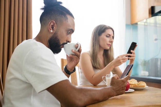 Uomo e donna che usano il telefono in cucina