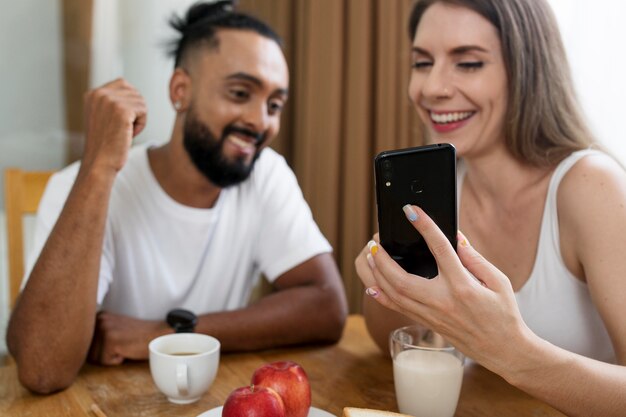 Uomo e donna che usano il telefono in cucina