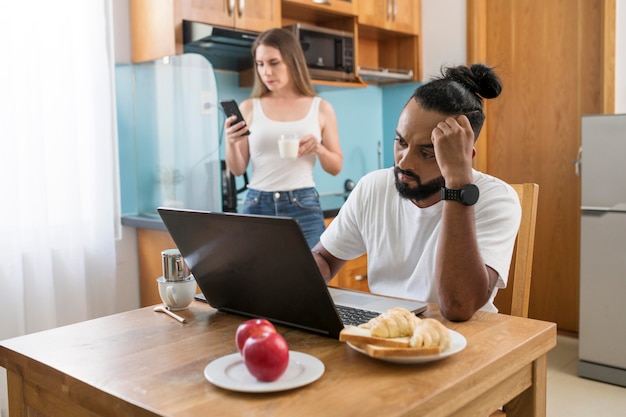 Uomo e donna che usano il telefono in cucina