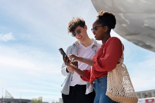 Uomo e donna che utilizzano smartphone fuori dal supermercato