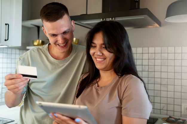 Uomo e donna che utilizzano tablet per lo shopping online con carta di credito