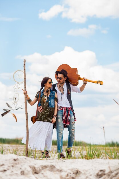 Uomo e donna come pantaloni a vita bassa di boho contro cielo blu