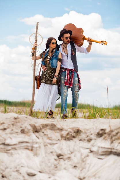 Uomo e donna come pantaloni a vita bassa di boho contro cielo blu