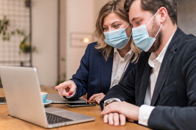 Uomo e donna di affari che parlano di un nuovo progetto mentre indossano maschere mediche