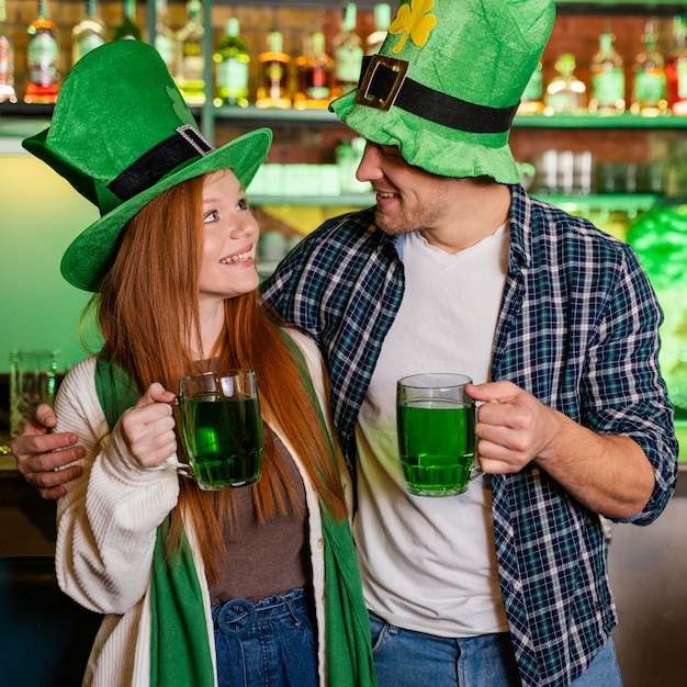 Uomo e donna di smiley che celebrano st. patrick's day al bar con drink