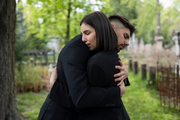 Uomo e donna in lacrime abbracciati al cimitero