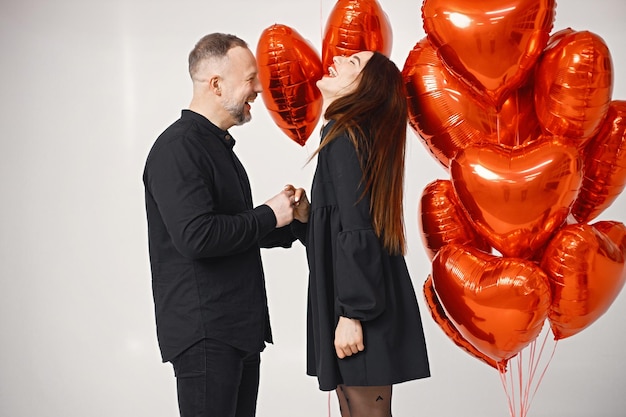 Uomo e donna in posa in studio vicino al mazzo di palloncini rossi a forma di cuore