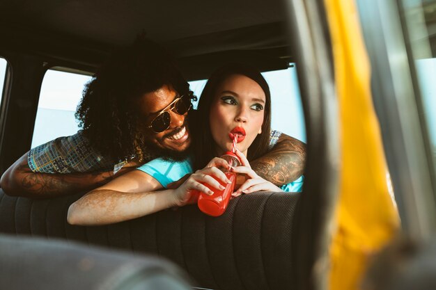 Uomo e donna in posa insieme in stile retrò all'interno del veicolo con succo