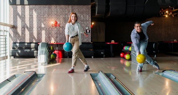 Uomo e donna lanciando palle da bowling sul vicolo