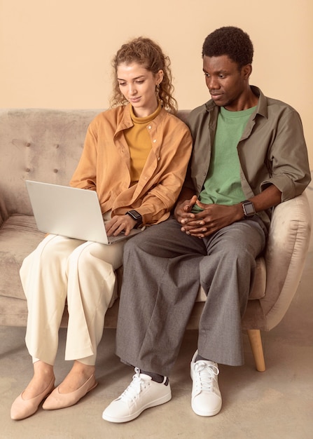 Uomo e donna seduti sul divano e utilizzando il computer portatile