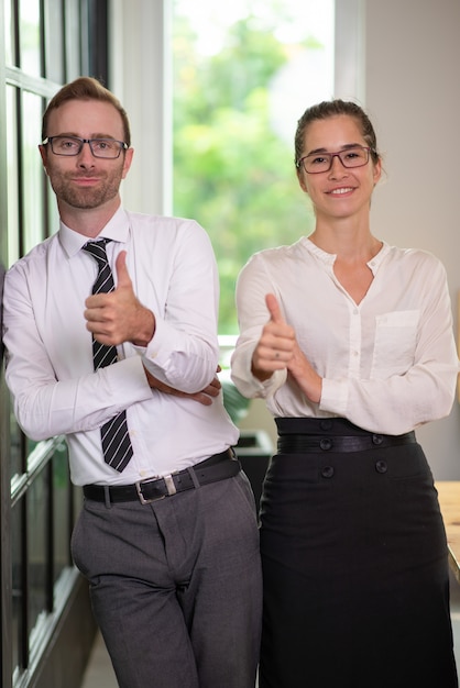 Uomo e donna sorridenti di affari che mostrano i pollici su.