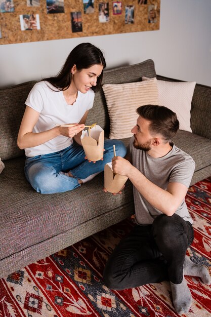 Uomo e donna sorridenti pranzando insieme a casa