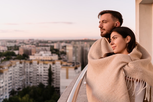 Uomo e donna sul balcone al tramonto in città