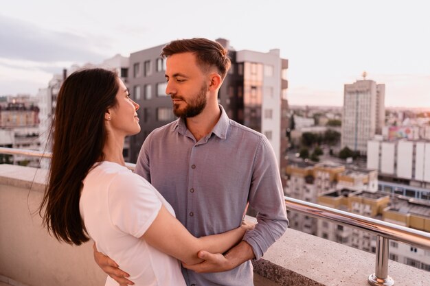 Uomo e donna sul balcone al tramonto in città