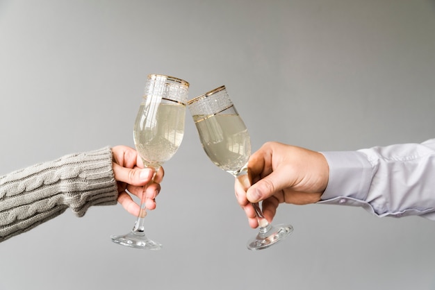 Uomo e donna tostatura flauto champagne su sfondo grigio